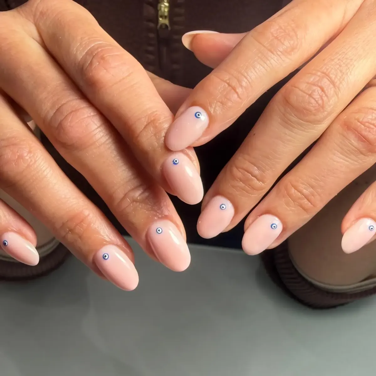 Nude almond-shape nails with evil-eye detail by Freda O'Reilly, Camden London